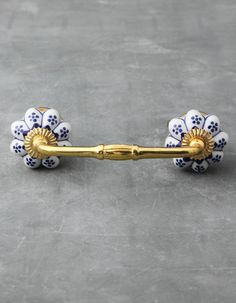 a gold handle with blue and white flowers on the end is sitting on a gray surface