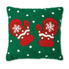 a green pillow with red mittens and snowflakes on it