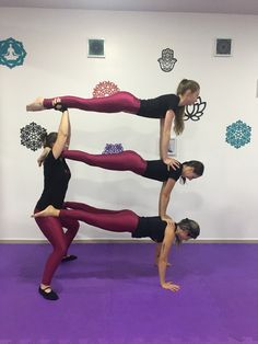 three women doing yoga poses in front of a wall