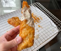 a person holding up a piece of food on a cooling rack