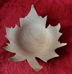 a wooden bowl sitting on top of a red towel next to a white plate with a leaf design