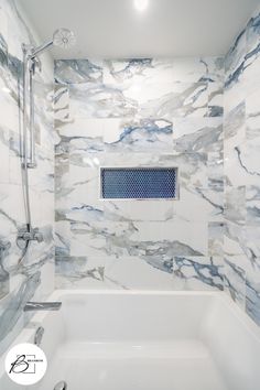 a white bath tub sitting under a window next to a shower head and faucet