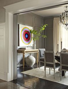 a dining room table with chairs and a painting on the wall in front of it