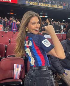 a woman is sitting in the stands at a soccer game and taking a selfie