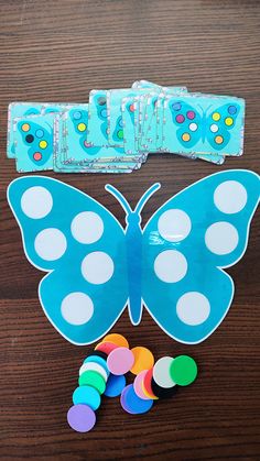 a blue butterfly with white polka dots on it's wings next to some colored buttons