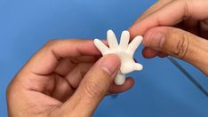 two hands holding small white objects against a blue background