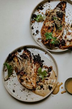 two dirty plates with food on them sitting next to a spoon and some sauces