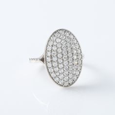 an oval shaped diamond ring set in white gold with pave diamonds on the sides