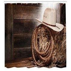 a cowboy's hat and rope on top of hay in front of a wooden wall