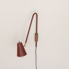 a wall lamp with a long arm and a red shade on the end, against a white background