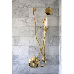 a shower head and hand held shower faucet in a white marble bathroom with gold fixtures