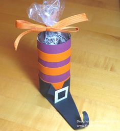 an orange and purple striped paper tube wrapped in plastic with a candy bag on top