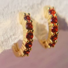 Add serious shine to your ear stack. These Garnet huggies are adorned with glistening gemstones adding a sense of royalty to your ensemble. These dainty garnet earrings hug tightly around the earlobe. Perfect for stacking with more huggies, studs or ear cuffs. Garnet is also known as January birthstones. D E T A I L S - Materials: 14k gold over sterling silver. They are 14k gold THICK plated, and they can last for a very long time with proper care. - Stone: 5 high-grade  garnet cz stones. - Inner diameter: 9mm. Outer diameter: 12mm. - Hypoallergenic, nickel, and lead-free. H O W ∙ T O ∙ O R D E R Select your gemstone in the drop-down menu.  O T H E R ∙ I N F O R M A T I O N * All items are nicely packaged and ready to gift in elegant jewelry boxes. * If you can't find the information you n Gift Round Hoop Earrings With Sparkling Stones, Red Huggie Earrings For Gift, Red Huggie Earrings Gift, Anniversary Huggie Earrings With Sparkling Stones, Huggie Earrings With Prong Setting As Gift, Small Hoop Huggie Earrings With Prong Setting As Gift, Cubic Zirconia Huggie Earrings With Sparkling Stones For Gift, Gift Huggie Earrings With Sparkling Cubic Zirconia, Small Hoop Huggie Earrings With Sparkling Stones For Gift