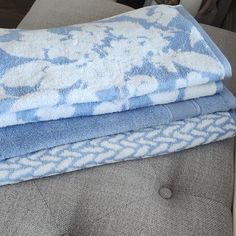 two towels folded on top of each other in front of a couch with a pillow