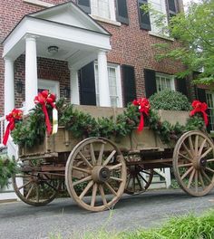 an old wooden wagon with christmas wreaths on the back is parked in front of a large brick building