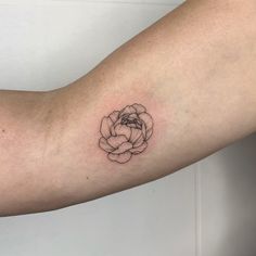 a black and white flower tattoo on the left arm, it looks like a rose