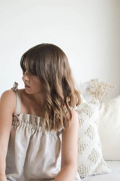 a woman sitting on top of a bed next to pillows