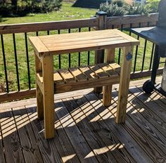 a wooden table sitting on top of a wooden deck next to a bbq grill