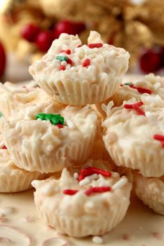 small white cupcakes with sprinkles on a plate next to christmas decorations