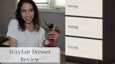 a woman holding a spray bottle in her hand next to a dresser with drawers on it