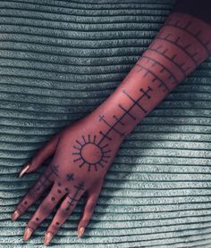 a woman's hand with tattoos on it and the sun in the middle of her arm