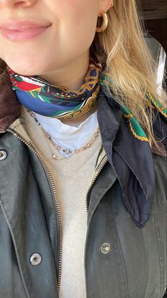 a close up of a person wearing a jacket and scarf with an earring on