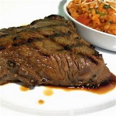 a white plate topped with meat next to a bowl of cole slaw