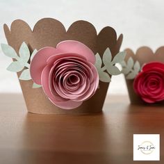 three paper flowers sitting on top of a table next to each other, one pink and the other red