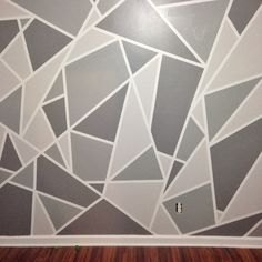 the wall is painted with gray and white geometric designs on it, along with wood flooring