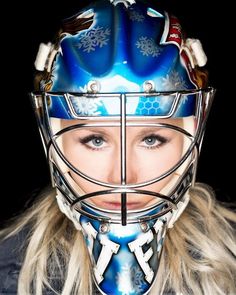 a woman wearing a hockey helmet and looking at the camera with her eyes wide open