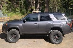 a gray four door suv parked in the woods