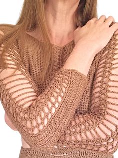 a woman wearing a brown sweater and holding her hand on her chest with both hands