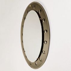 an oval mirror hanging on the wall with rivets and screws around it