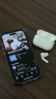 an iphone and ear buds sitting on a table next to each other with the same device in front of them