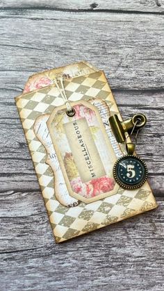 an old fashioned tag is attached to a wooden surface with a metal keychain