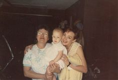 an older man holding a baby while standing next to two women