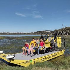 a group of people sitting on the back of a yellow boat