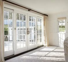 the sun shines through the windows in this room with white walls and curtains on either side of the glass doors