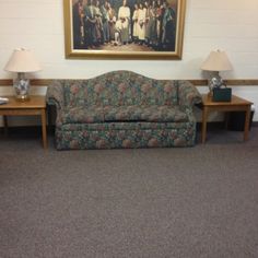 a living room with a couch and two tables in front of a painting on the wall