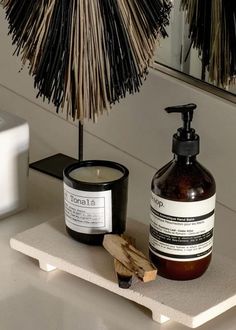 a bottle of lotion sitting next to a candle on a shelf in front of a mirror