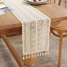 a white table runner with tassels on it sitting on top of a wooden table