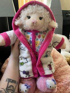 a person holding a stuffed animal with hello kitty on it's chest and wearing a pink hoodie