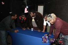 several men standing around a blue table in a room