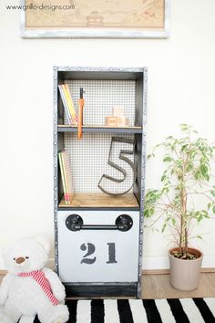 a white teddy bear sitting in front of a book shelf with numbers on it and a small potted plant