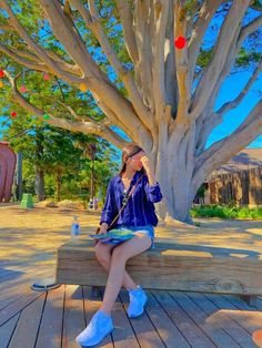 a woman sitting on a bench in front of a tree