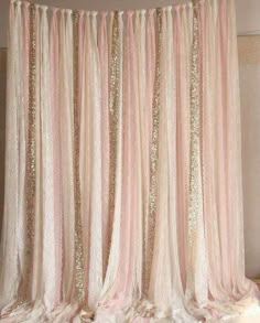 a pink and gold curtain with sequins hanging from it's side in front of a wall