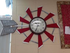 a clock mounted to the side of a wall with red and white strips on it