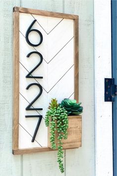 a wooden sign with succulents on it hanging from the side of a building