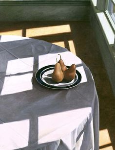 two pears on a plate sitting on a table in front of a window with sunlight streaming through it