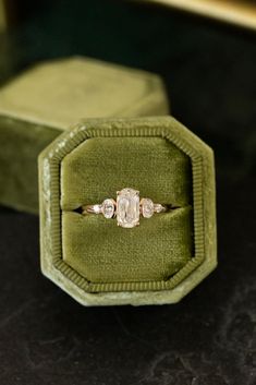 an engagement ring in a velvet box on top of a black table with green velvet